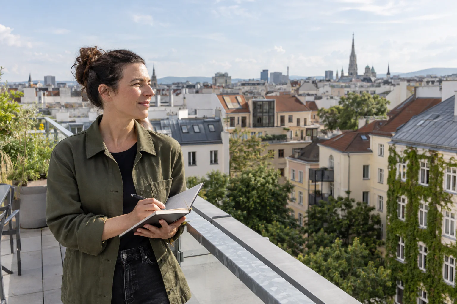 Technikerin betrachtet von einer Dachterrasse Wiener Wohnhäuser